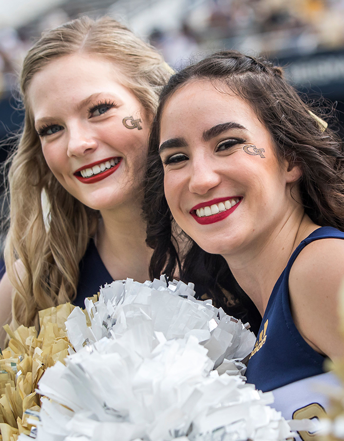 Two GT female cheerleaders holding pom-poms.