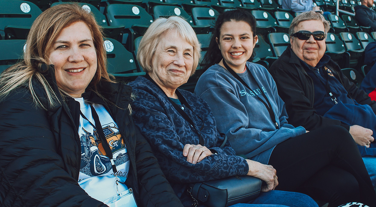 Mother, grandma, daughter, and grandma sitting at a baseball game.