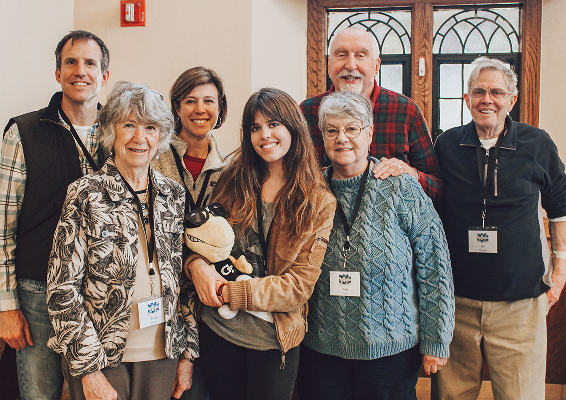 Two sets of grandparents, parents and grand-daughter holding a Buzz doll.