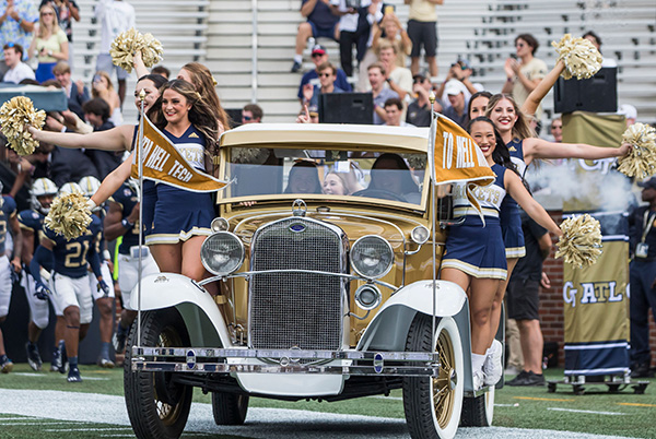 Ramblin' Wreck entering the football field with cheerleaders.