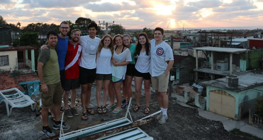 A group of students on a rooftop. Dilapidated houses can be seen in the distance.