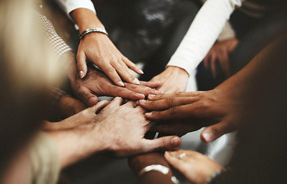 Group of multiethnic hands holding symbolizing teamwork.