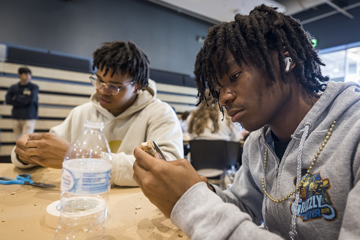 Two young men look intently at the pottery in their hands as they paint