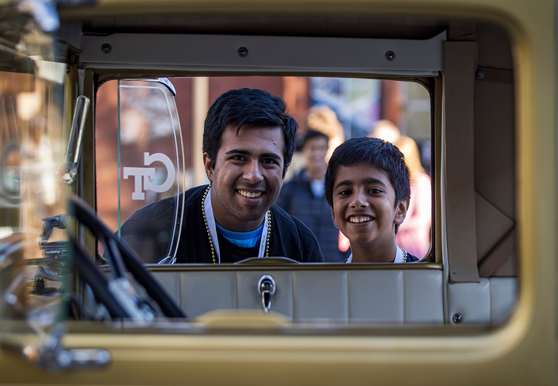 The faces of a young man and a child are framed through the open windows of a car
