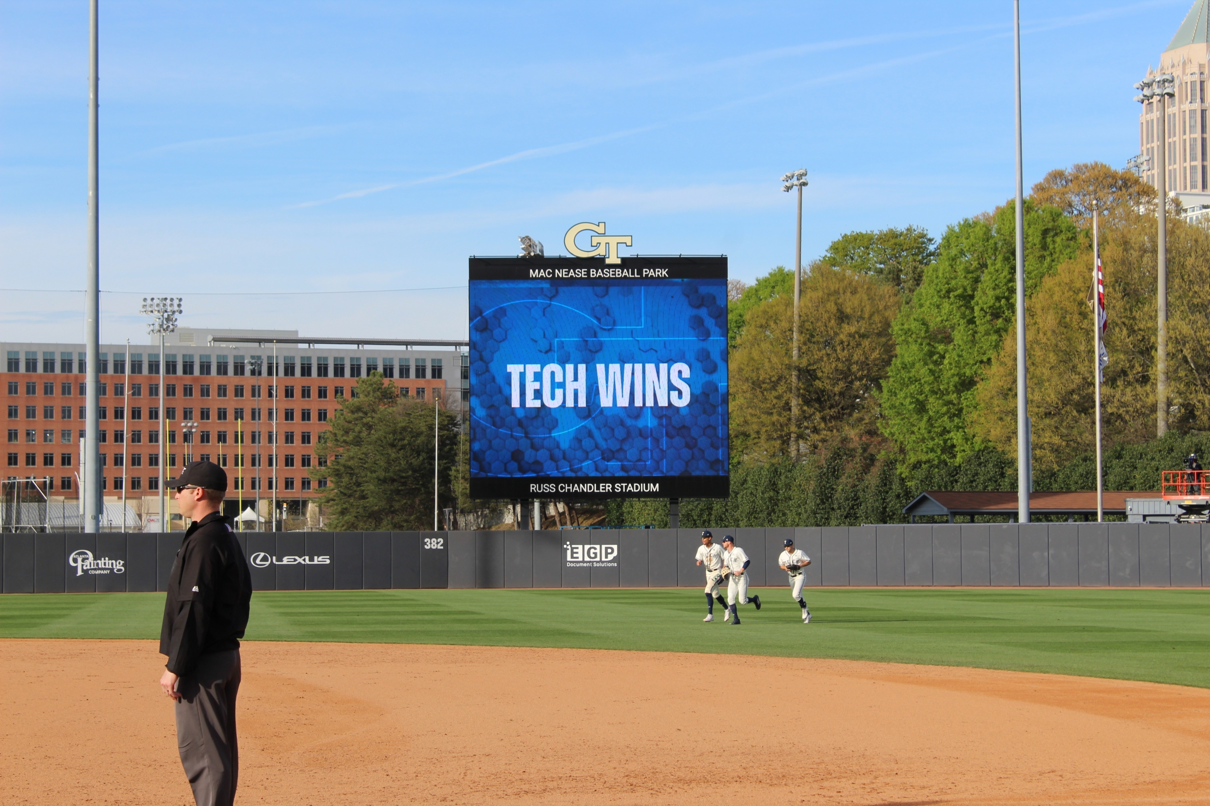 An LED sign on a baseball field reads "TECH WINS"